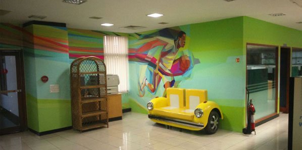 Green forest mural in an EdgeVerve lounge with a vintage-car styled sofa.